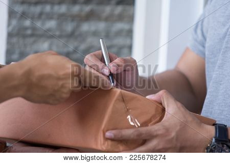 Close Up Man Hand Appending Receive Sign Signature After Accepting A Delivery Of Boxes