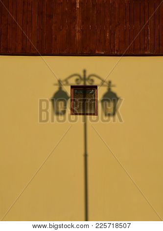 Symmetrical Shadow From An Old Lantern On A Yellow Brown Wall