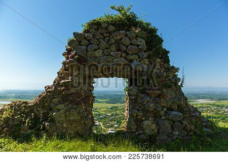 An Abandoned Fortress In The Mountains, Overgrown With Grass Against The Background Of Mountains And