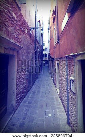 Street Called Calle In Italian Language  Between Tall Houses In Venice Italy