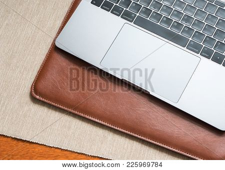 A Laptop Computer With A Leather Case On The Table