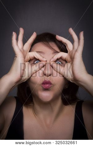 Woman Grimaces In Front Of Camera On Black Background