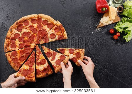 Pepperoni Pizza On A Black Background Texture. Still Life With Hands And Ingredients. Copy Space.