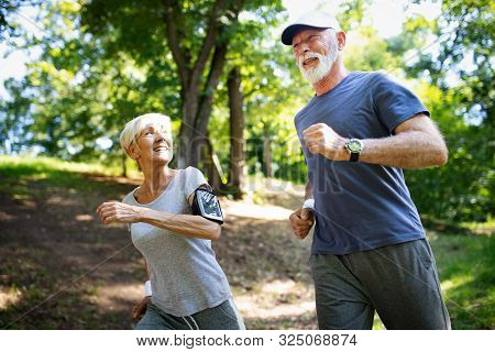 Mature Or Senior Couple Doing Sport Outdoors, Jogging In A Park