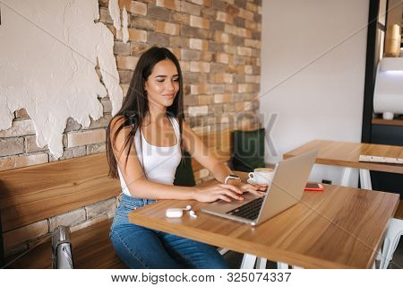 Attractive Smart Girl Working On Laptop In Cafe. Beautiful Girl Using Computer For Work. Girl Grinki