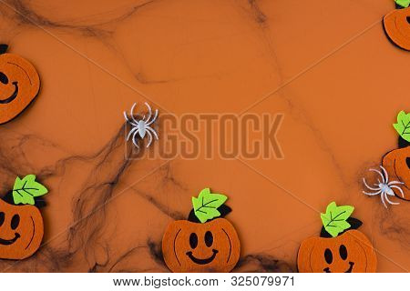 Top View Of Halloween Crafts, Felt Handmade Pumpkins, Black Patina On Orange Paper Background With C