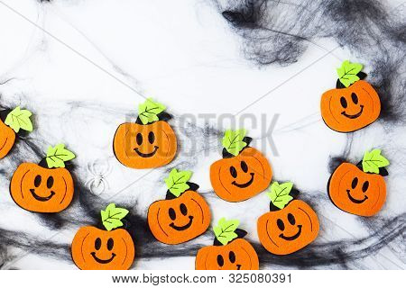 Top View Of Halloween Crafts, Felt Handmade Pumpkins, Black Patina On White Paper Background With Co