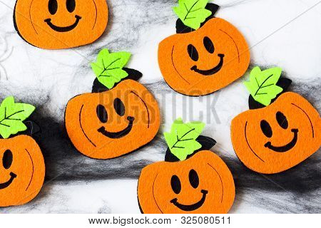 Top View Of Halloween Crafts, Felt Handmade Pumpkins, Black Patina On White Paper Background T. Hall