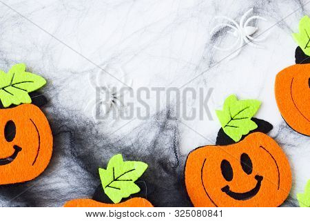 Top View Of Halloween Crafts, Felt Handmade Pumpkins, Black Patina On White Paper Background With Co