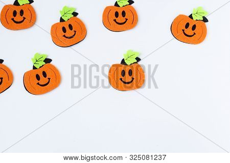 Top View Of Halloween Crafts, Felt Handmade Pumpkins On White Paper Background With Copy Space For T