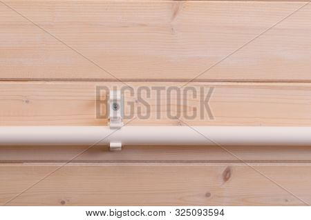 On A Light Wooden Wall, Polypropylene Pipe, Fixed In One Of Two Mounts