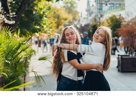 Happy Brightful Positive Moments Of Two Stylish Girls Hugging On Street In City. Closeup Portrait Fu