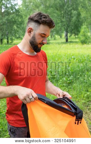 Young Man Takes Air Into Air Sofa, Lamzak. Man Tries To Inflate Air Lounger. In The Green Summer Bac