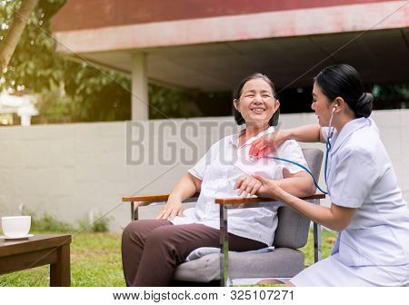 Nurse Using Stethoscope Checking To Asian Senior Woman Patient For Listening Heart Rate At Home
