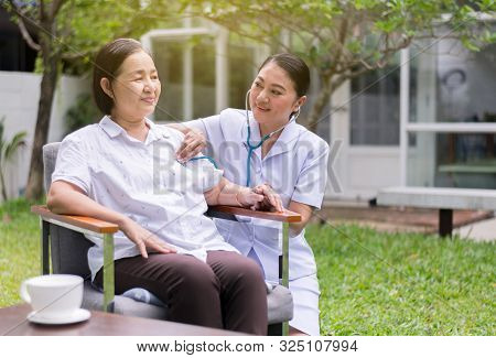 Nurse Using Stethoscope Checking To Asian Senior Woman Patient For Listening Heart Rate At Home