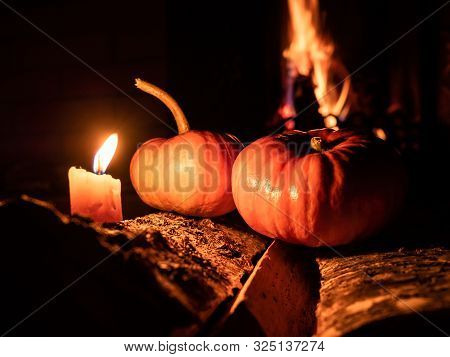 Two Halloween Pumpkins In The Dark On Birch Logs Burning Candles. In The Background Is A Flame From