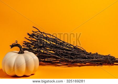 White Pumpkins And Black Broom Thanksgiving Theme On An Orange Background With Room For Text