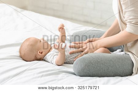 Baby Healthcare. Woman Massaging Tummy Of Her Son Preventing Colics, Crop