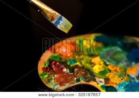 Oil Paint Palette And Paint Brush On Black Background
