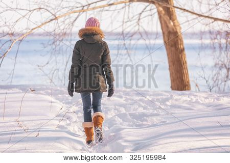 Winter walk woman walking out on nature river background in cold outdoor nature river outside wearing wool hat, scarf and fur jacket outerwear enjoying outdoors.