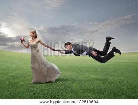 Impaciente esposa feliz tirando a su marido por su brazo y corriendo en un prado verde