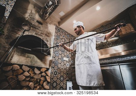 Tasty Stonebaked Pizza Is Ready And Italian Chef Is Removing It From Oven.