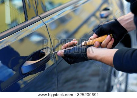 Closeup Male Hands In Black Gloves Is Trying To Open, Break Into Automobile Without Signaling Alarm.