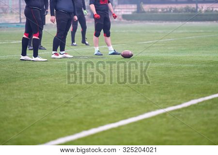 group of young professional american football players practicing football kickoff during training on the stadium field with focus on the legs