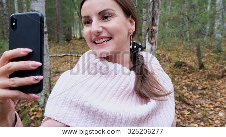 A Young Woman Takes Selfie On The Phone With Pleasure In The Spring Forest And Smiles. Slow Mo. Clos