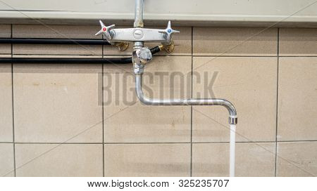 On The Wall There Is A Running Kitchen Faucet In A Laundry Room