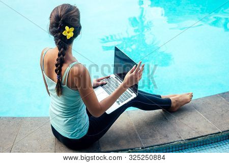 Young Businesswoman Sitting With Laptop On Vacation Near The Pool