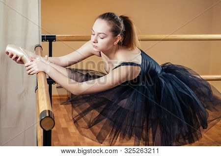 Young And Beautiful Woman In Ballet Dress And Pointe Dance. The Ballerina Warms Up In The Classroom.