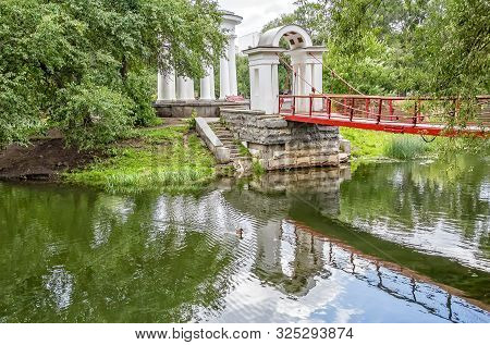 Suspension Bridge And Rotunda On A Small Island On A Pond In The Park On A Summer Day. Park Of The R
