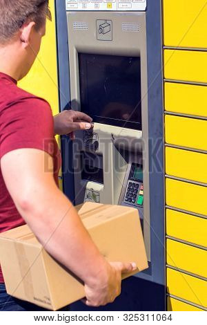 Man Client Using Automated Self-service Post Terminal Machine Or Locker To Depisit A Parcel For Stor