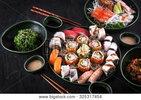 Assorted Sushi Set Served On Dark Stone Slate Background. Seaweed Wakame Salad, Seafood, Various Mak