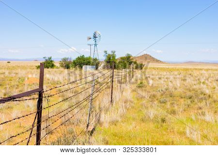 Windmill On A Farm In Rural Grassland Area Of South Africa