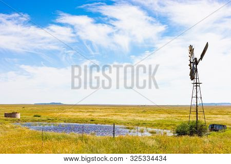 Windmill On A Farm In Rural Grassland Area Of South Africa