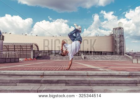 Male Athlete, Guy Dancer Summer City. Standing One Arm Jump. Fashionable Modern Break Dance Style Fa