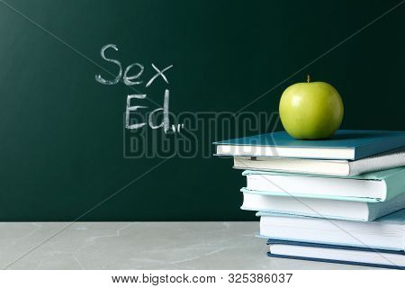 Books And Apple On Grey Table Near Chalkboard With Phrase 