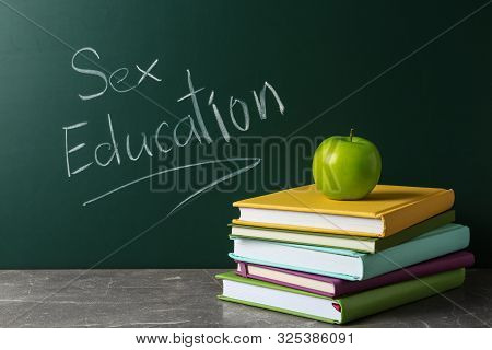 Books And Apple On Grey Table Near Chalkboard With Phrase 