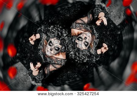 Two scary and beautiful Katrina Calavers looking up at camera over dark background. Fashion model with sugar skull makeup. Dia de los muertos. Day of The Dead. Halloween.
