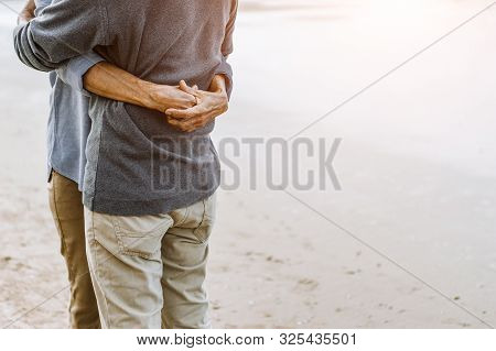 Asian Senior Couple Or Elderly People Walking And Siting At The Beach On Their Weekend Vacation Holi