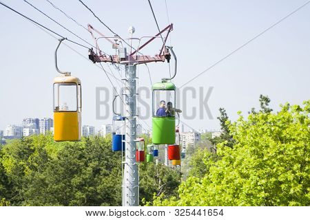 Kharkov, Ukraine - April 30, 2018: Three Colourful Cabins On Rope In The City Park. Panorama Of Cabl