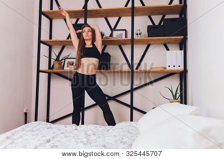 Attrctive Fitness Woman Doing Stretching Exercises At Home, As Part Of A Healthy Lifestyle Without G