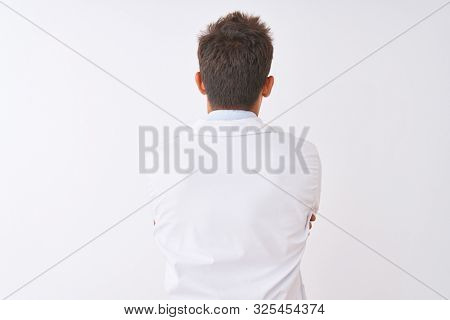 Young handsome sciencist man wearing glasses and coat over isolated white background standing backwards looking away with crossed arms