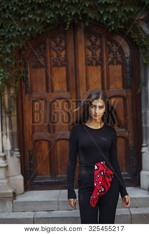 Stylish Brunette Standing Next To The Entance To A Building