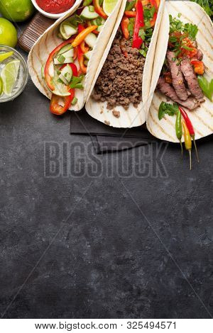 Set of mexican tacos with meat and vegetables in tortilla. And caipirinha cocktail. Top view on stone table. Flat lay with copy space