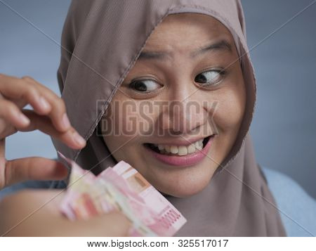 Portrait Of Indonesian Muslim Woman Receiving Rupiah Money, Smiling Joyful Gesture