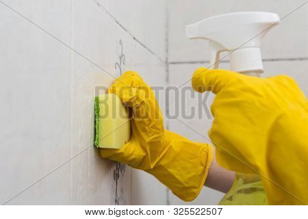 Cleaning The Tile Wall With A Sponge And Spray.