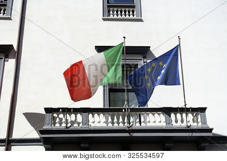 Italian And European Flags Waving On Italian Building. Concept For Italexit, Euroscepticism, Pro-eur